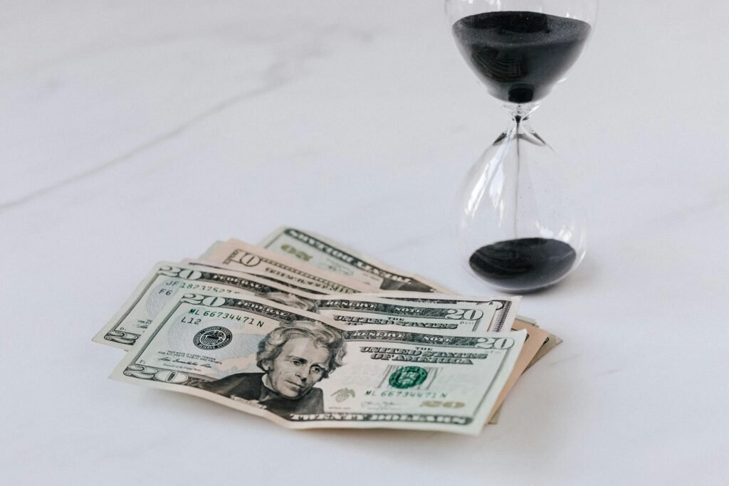 From above of transparent glass with black sand on white table and pile of paper money with image of president