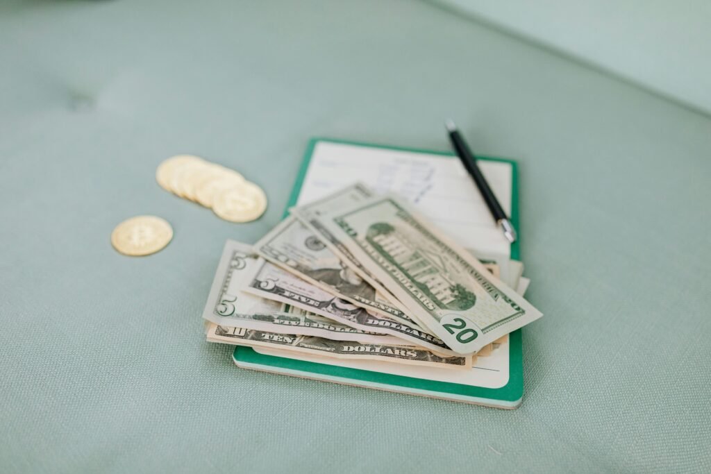 Close-up of American dollar bills and coins on a journal with a pen, representing budget planning.