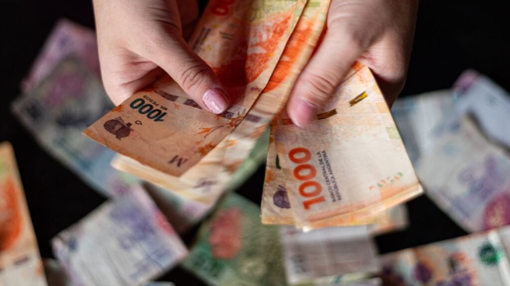 Close-up of hands holding Argentine peso bills in Buenos Aires.