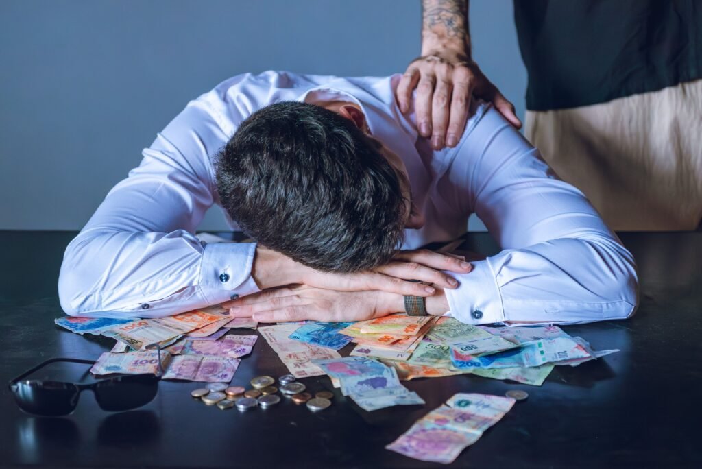 Stressed businessman rests on table with Argentine pesos in Buenos Aires.
